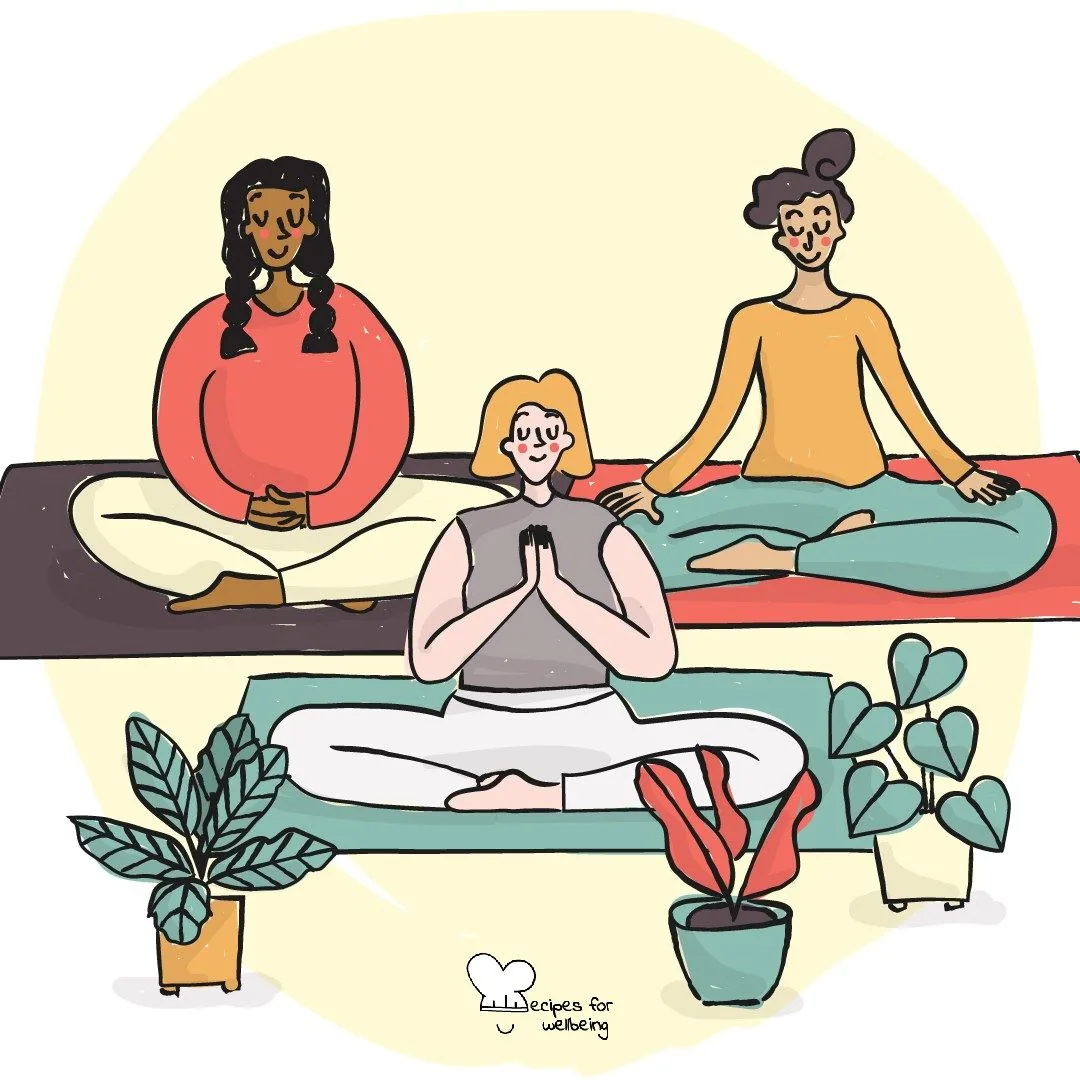 Three people sitting cross-legged among plants, hands resting together