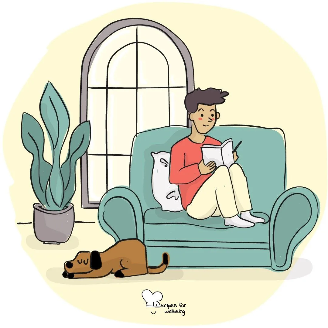 A person reading on a sofa with a dog asleep on the floor beside them