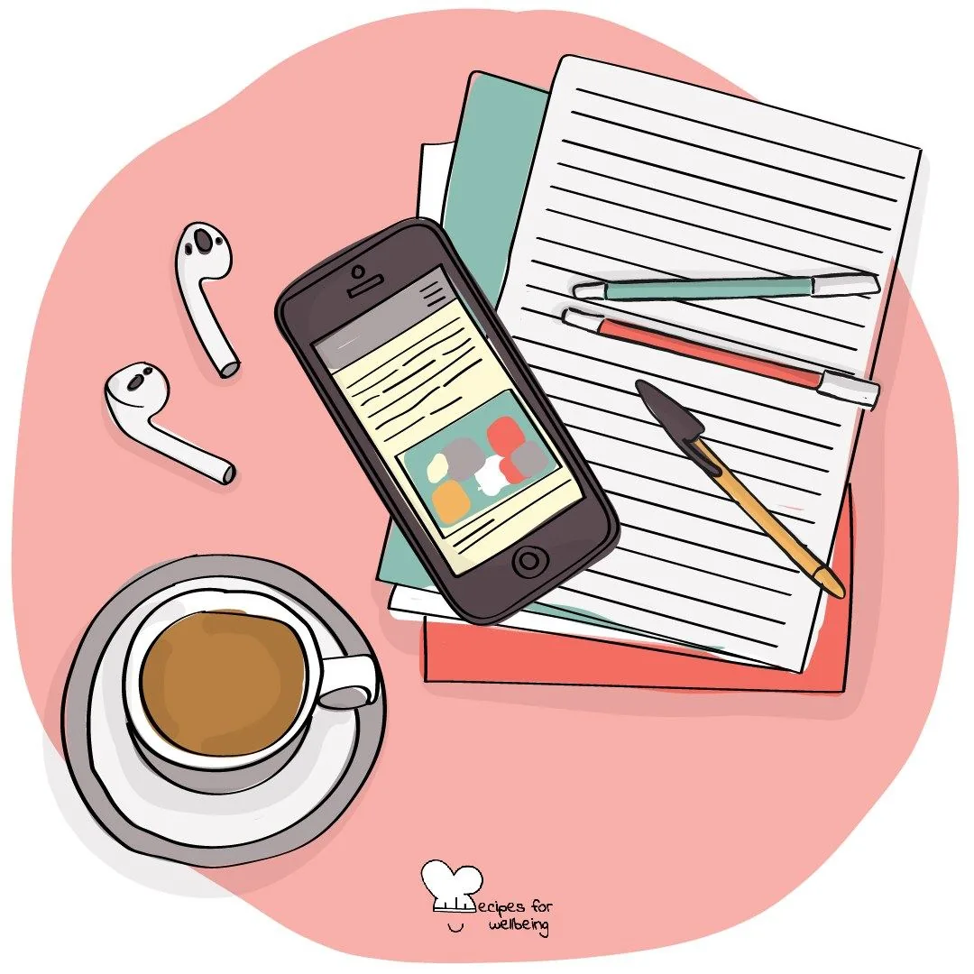 A phone and earbuds set beside an open notebook and a cup of coffee